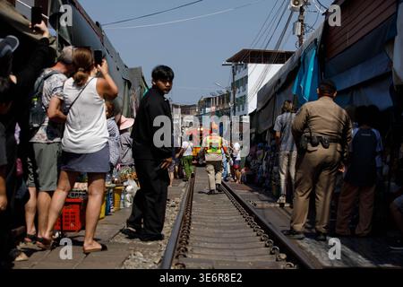 SAMUT SONGKHRAM, TAILANDIA-Mar 28, 2026: Treno diesel che passa il mercato degli ombrelli pieghevoli nella piattaforma, ampia vista, al mercato di Maeklong. Foto Stock