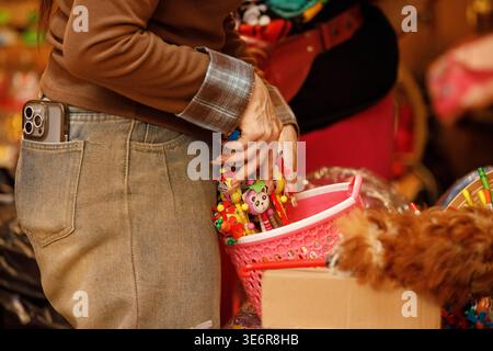 SAMUT SONGKHRAM, THAILAND-Mar 28, 2026: Fornitore donna che organizza prodotti in vendita, primo piano, al mercato di Maeklong. Foto Stock
