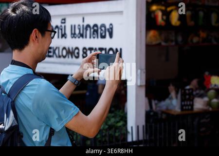SAMUT SONGKHRAM, THAILAND-Mar 28, 2026: Backpacker maschio che scatta foto con smartphone, fotografia digitale di viaggio e stile di vita, profilo laterale Foto Stock