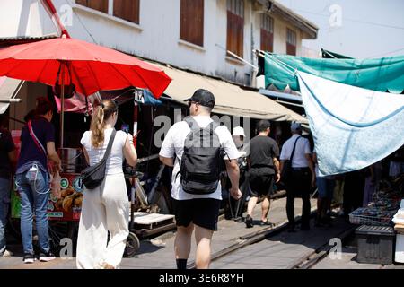SAMUT SONGKHRAM, THAILAND-Mar 28, 2026: Turisti che esplorano le merci al mercato ferroviario pieghevole Maeklong, vista posteriore, a Maeklong. Foto Stock