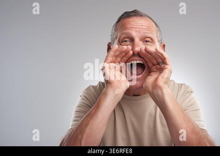Annuncio, ritratto e urla con l'uomo in studio per allertare, parlare forte o promuovere. Attenzione, notizie e rumore con la voce urlante di maturo Foto Stock
