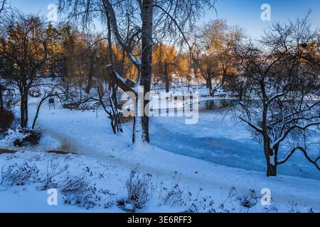 Parco Moczydlo paesaggio invernale con laghetto ghiacciato al tramonto nella città di Varsavia, Polonia. Foto Stock