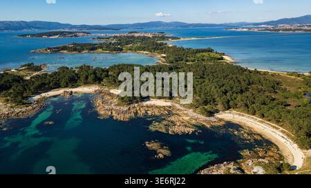 Uno splendido panorama aereo del Parco naturale di Carreirón. Le acque cristalline turchesi si insinuano su piccole insenature di sabbia bianca, circondate da una densa prua di pino Foto Stock