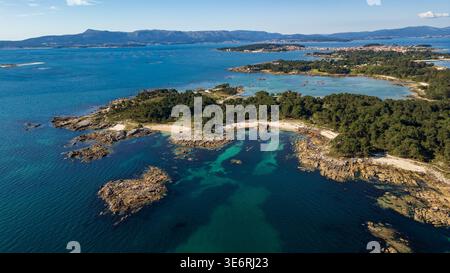 Uno splendido panorama aereo del Parco naturale di Carreirón. Le acque cristalline turchesi si insinuano su piccole insenature di sabbia bianca, circondate da una densa prua di pino Foto Stock