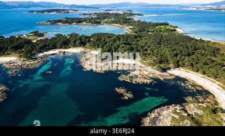 Uno splendido panorama aereo del Parco naturale di Carreirón. Le acque cristalline turchesi si insinuano su piccole insenature di sabbia bianca, circondate da una densa prua di pino Foto Stock