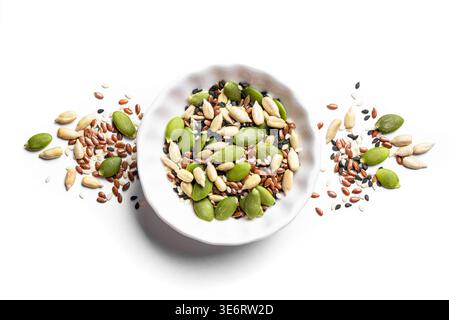 Mescolare i semi in una ciotola bianca isolata su sfondo bianco, vista dall'alto, elemento di design. Consistenza sana degli ingredienti alimentari. Semi di zucca, bianco e nero Foto Stock