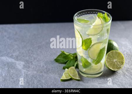 Cocktail mojito fresco con lime, menta e ghiaccio in vetro su sfondo scuro Foto Stock