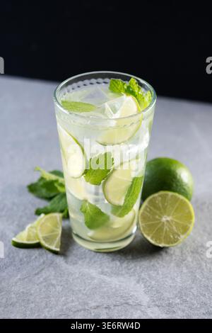 Cocktail mojito fresco con lime, menta e ghiaccio in vetro su sfondo scuro Foto Stock