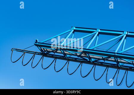 L'immagine mostra un telaio in acciaio sospeso nell'aria in un cantiere. La struttura è blu ed è posta contro un cielo azzurro. Questa scena Foto Stock