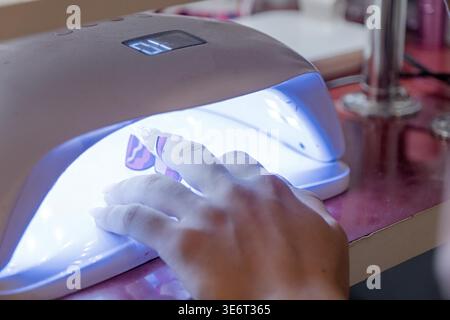 Dall'alto del raccolto, manicurista irriconoscibile che fa nail art per cliente femminile nel salone di bellezza Foto Stock