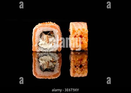 Due sushi involtini avvolti nel salmone, uno con sezione trasversale e ripieno di anguille grigliate e formaggio spalmabile, uno cotto con una parte dorata croccante e sale marino, Foto Stock