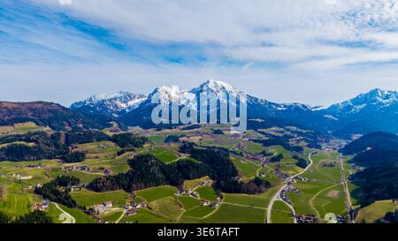 Veduta aerea di campi verdeggianti che contrastano con le cime innevate sotto un cielo luminoso, Windischgarsten, alta Austria, Austria. Foto Stock