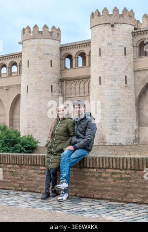 Ritratto di una giovane coppia nella fortezza del Palazzo Aljaferia a Saragozza, Spagna. Viaggiatori romantici che posano sullo sfondo di antiche torri di pietra Foto Stock