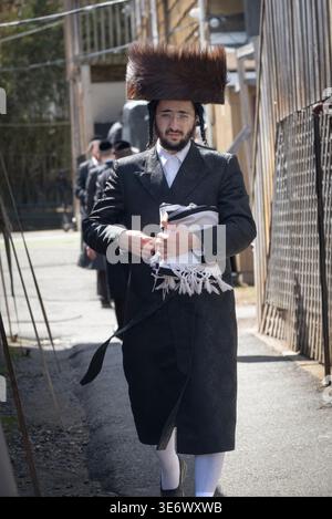 Un ebreo chassidico che indossa un cappello di pelliccia di shtreimel lascia una sinagoga dopo le preghiere mattutine di Passsover. Nella contea di Rockland, New York, 2026. Foto Stock