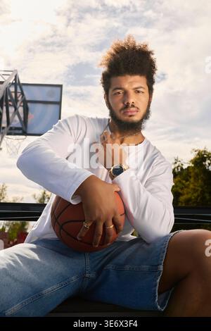 Un giovane gioca a basket all'aperto, dimostrando abilità e sicurezza in campo. Foto Stock