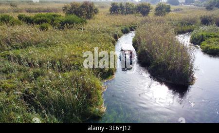 Vista aerea dall'alto verso il basso del fiume Azmak cristallino con barche e canne da tour ad Akyaka in Turchia Foto Stock