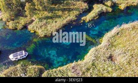 Vista aerea dall'alto verso il basso del fiume Azmak cristallino con barche e canne da tour ad Akyaka in Turchia Foto Stock
