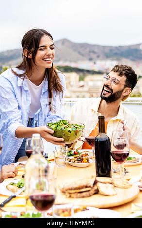 Gli amici si godono la cena estiva sulla terrazza sul tetto Foto Stock