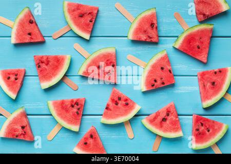 Fette di frutta succosa su bastoni di legno, sfondo blu Foto Stock