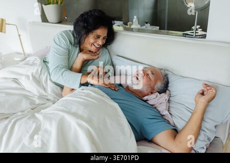 Donna di coppia afroamericana anziana appoggiata su un uomo a letto, sorridente e mostra affetto mattutino Foto Stock