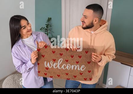 Giovane coppia con tappetino in corridoio il giorno del trasloco Foto Stock
