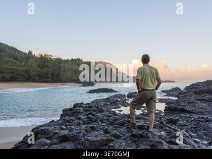Senior caucasico si affaccia sulle rocce e sull'oceano della spiaggia di Lumahai a Kauai nelle isole Hawaii Foto Stock