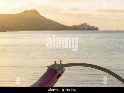 La mattina presto sorgere del sole all'alba illumina outrigger del tradizionale canoa hawaiana dal Diamond Head e Waikiki Beach area di Oahu in Hawaii Foto Stock