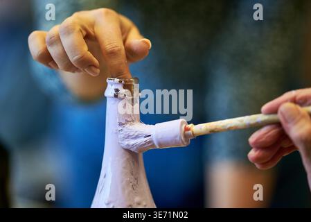 Primo piano del dito di una persona anziana che tiene una bottiglia di vetro mentre viene dipinto viola, Katowice, Voivodato della Slesia, Polonia, Europa Foto Stock