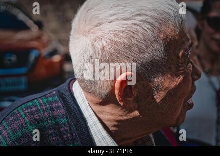 Taoyuan, Taiwan - 11 febbraio 2024: Primo piano illuminato dal sole di un anziano uomo asiatico con capelli bianchi e pelle rugosa in un sereno momento all'aperto. Foto Stock