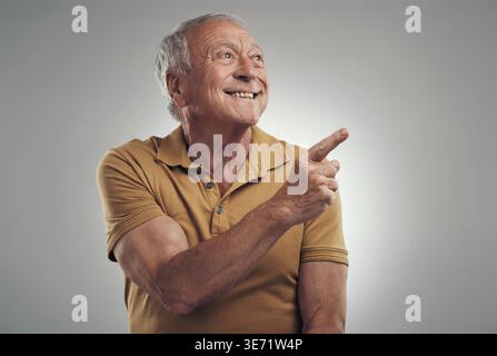 Studio, punta e senior man con sorriso, sconto assicurazione sulla vita e annuncio per offerta limitata. Promozione politica, felice e vecchio con Foto Stock