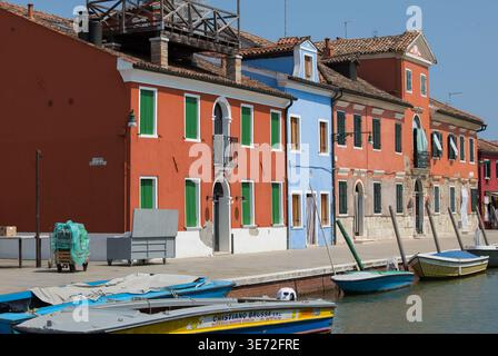 Burano, Italia - 25 giugno 2025: Edifici vivaci lungo il canale di Burano, Italia, si riflettono splendidamente nell'acqua, creando un'atmosfera affascinante Foto Stock