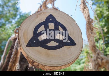 Simbolo di Triquetra dipinto sulla fetta di tronco dell'albero. Ricostruzione del campo militare celtico. Foto Stock