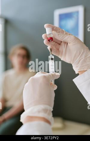 Medico preparazione iniezione di vaccino per adolescenti in clinica Foto Stock