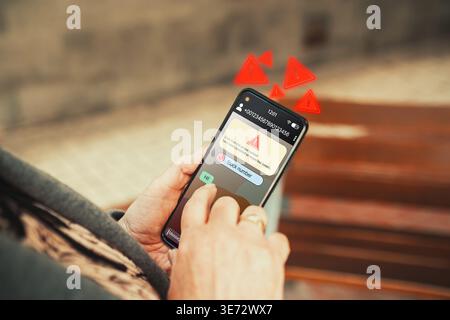 Avviso di messaggio di testo truffa con avviso numero di blocco sullo smartphone tenuto da una donna matura. Autoprotezione digitale, mishing e frode SMS. Foto Stock
