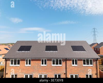 Il tetto di una fila di case di nuova costruzione in un cantiere con tetto integrato o pannelli solari a tetto per un'energia economica e sostenibile in un ambiente ecologico Foto Stock