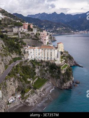 Vista aerea della città di Atrani e degli edifici arroccati lungo la Costiera Amalfitana, dove le aspre scogliere incontrano il mare turchese di Atrani, Italia. Foto Stock