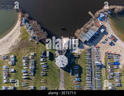 Vista aerea delle barche allineate perfettamente sulla riva erbosa vicino a un porticciolo con spiagge sabbiose che incontrano le acque scure di Almere, Flevoland, Paesi Bassi. Foto Stock
