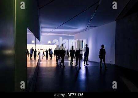 Sagome di persone che camminano attraverso il Museo Ebraico di Berlino installazione con illuminazione ambiente blu e riflessi su superfici lucide Germania Foto Stock
