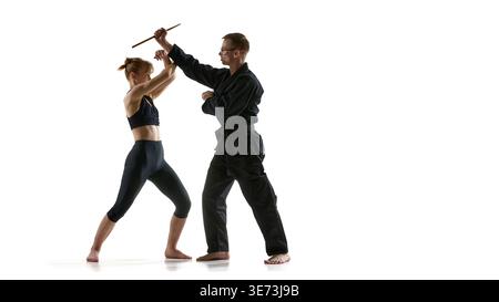 Donna che blocca l'attacco con bastone mentre l'uomo dimostra la tecnica di difesa delle armi. Foto Stock