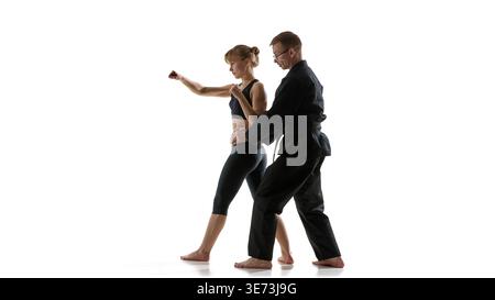 Uomo che guida la donna tecnica di pugno mentre corregge il movimento dell'anca durante l'allenamento Foto Stock