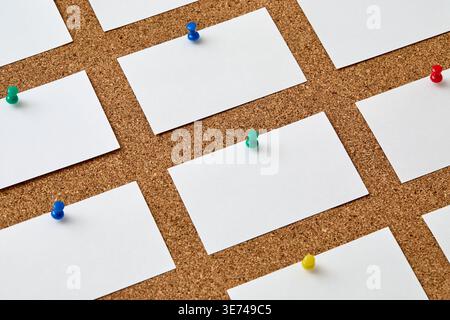 Pezzi di carta vuoti attaccati al bordo di sughero con perni colorati Foto Stock