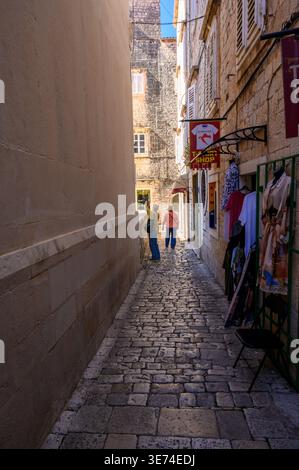 Una strada molto stretta e acciottolata con due turisti nel centro storico di Traù in Croazia. Foto Stock