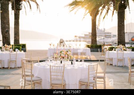 Festa del tramonto sulla spiaggia. Elegante festa sul lungomare con vista sul tramonto e arredi raffinati Foto Stock