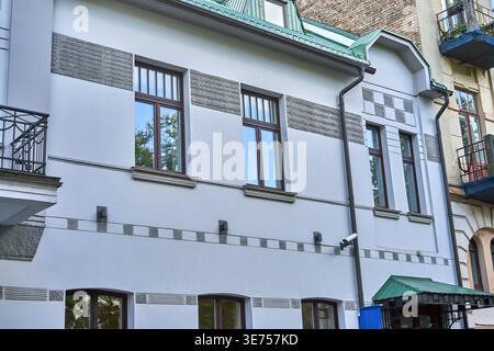 L'immagine mostra la facciata di un edificio residenziale urbano rinnovato con un esterno bianco o grigio chiaro e una texture grigia decorativa Foto Stock