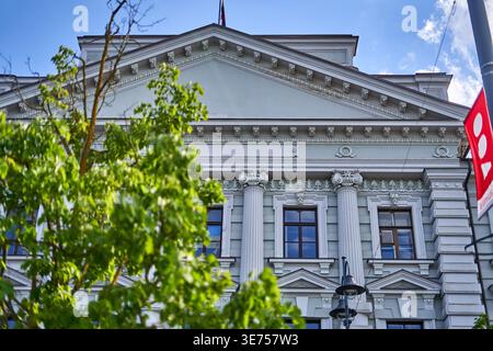 Una vista a bassa angolazione di un grande edificio neoclassico con dettagli architettonici ornati tra cui colonne corinzie, frontone decorativo con Foto Stock