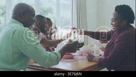 Versare bicchieri per famiglie multi-generazionali al tavolo da pranzo di casa, con caraffa e fragole Foto Stock