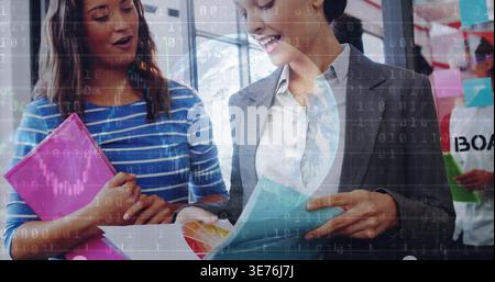 Recensisci due donne, blazer grigio che indica carte e campioni in ufficio con cartelle rosa blu Foto Stock
