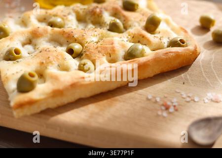 Primo piano della tradizionale focaccia italiana alle olive su tavola di legno con spazio per le copie. La foto ad alto angolo mette in risalto olive verdi croccanti e croccanti con crosta dorata e secche Foto Stock