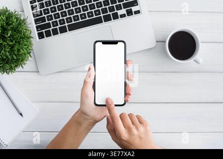 Utilizzare lo smartphone a mano su sfondo bianco in legno Foto Stock