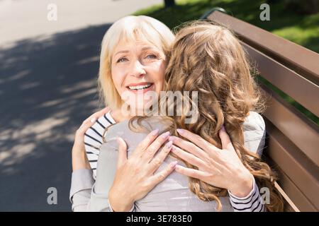 Madre anziana che abbraccia con figlia nel parco Foto Stock